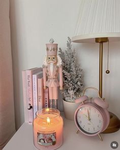 a pink candle sitting on top of a table next to a clock and other items