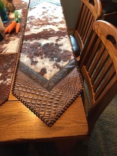 a wooden table topped with a brown and white cow print placemat on top of a wooden chair