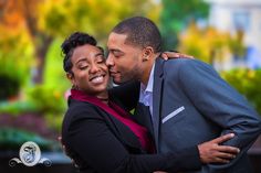 a man and woman embracing each other in front of trees