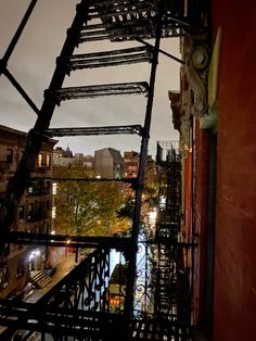 a fire escape on the side of a building at night with city lights in the background