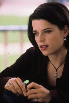 a woman holding a cell phone in her right hand and looking at the camera with an intense look on her face