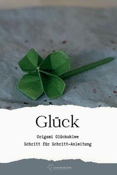 an origami clover sitting on top of a piece of paper with the words gluck written below it