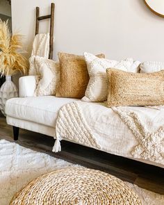 a white couch sitting on top of a wooden floor next to a mirror and rug