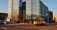 a yellow trolley is going down the street in front of a tall building with many windows