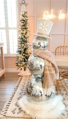 a christmas tree with disco ball decorations and a snowman hat on top in front of a window