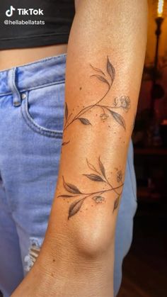 a woman's arm with a tattoo on it that has flowers growing out of it