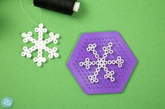 a snowflake made out of plastic beads next to a spool of thread