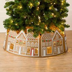 a small christmas tree in a gold tin with houses and lights on the top is lit up