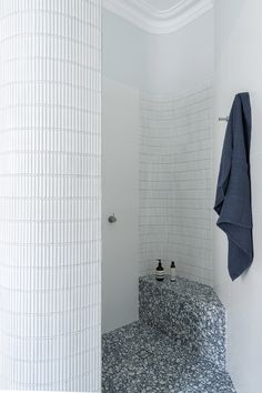 a white tiled bathroom with blue towels hanging on the wall and two black soap dispensers