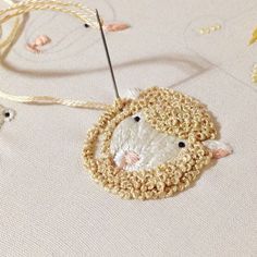 a sheep ornament hanging from a thread on a white tablecloth with gold trim