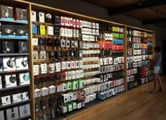 a woman standing in front of a wall full of cell phones and boxes on display