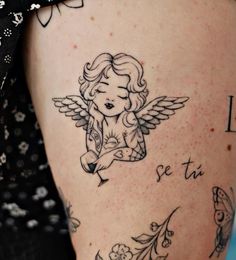 a woman's thigh with tattoos on her legs and an angel tattoo on the leg