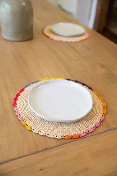 two white plates sitting on top of a wooden table next to a vase filled with flowers