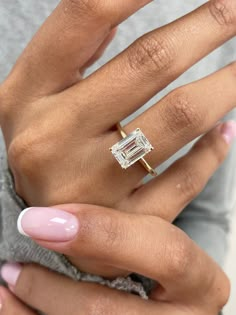 a woman's hand with a pink manicured nail polish and an engagement ring