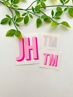 two stickers with the letters h and j on them next to some green leaves