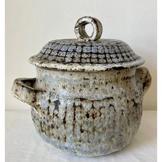 an old ceramic pot with a lid and handle