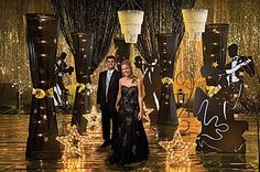 a man and woman standing in front of an elaborately decorated stage with lights on it