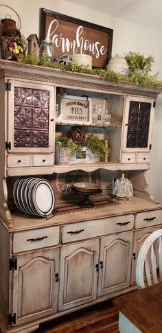 an old china cabinet is decorated with greenery and plates on it's top