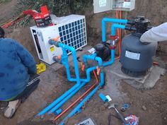 two men are working on an air conditioner and water heater in the dirt