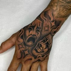 a man's hand with a tattoo on it and two faces in the middle