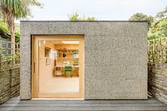 an open door to a room with a table and chairs on the outside, surrounded by greenery