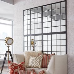 a living room with a white couch and some pillows on the floor next to a window