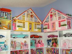 a room filled with lots of toys and dolls on top of white bookshelves