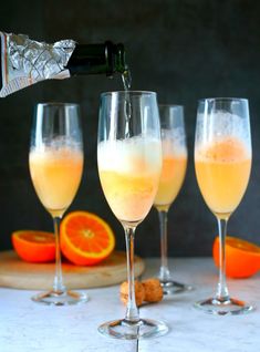 champagne being poured into wine glasses with an orange slice and crackers on the side