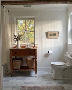 a white toilet sitting next to a window in a bathroom