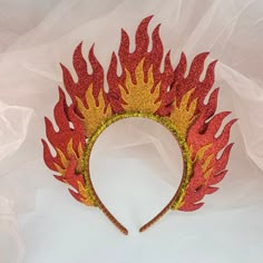 a red and yellow fire headband with flames on it's side sitting on a white sheet