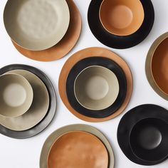 six black, brown and white plates are arranged in a circle on a table top