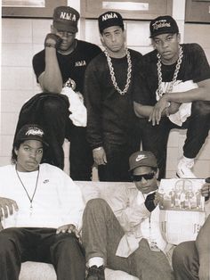 a group of young men sitting next to each other in front of a white wall