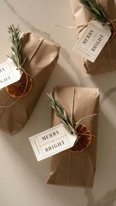 three wrapped packages with rosemary and orange slices tied to them, sitting on a table