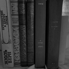 a row of books sitting on top of a white shelf next to a window in a black and white photo