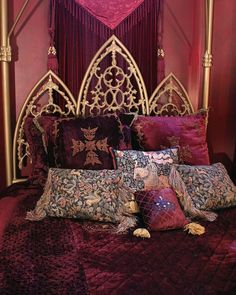 a bed with many pillows on it and a canopy over the headboard is covered in purple fabric