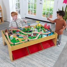 two young boys playing with a toy train set