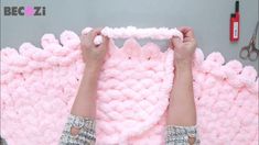 someone is making a pink knitted blanket out of yarn