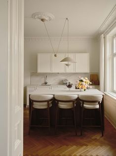 a kitchen with three stools and a center island in the middle of the room