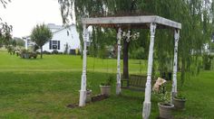 a wooden gazebo with potted plants on the ground and trees in the background