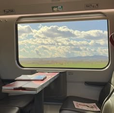 the inside of a train car with a table and chairs in front of an open window