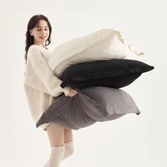 a woman is holding three pillows in the air