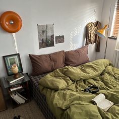 an unmade bed in a bedroom with green sheets and brown comforter on it