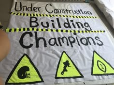 a construction sign that says under construction, building champions and football helmets on it