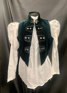 Steampunk Vest Gothic medieval pirate This comes with the following 3 items:- 1 Bottle green velvet waistcoat fully lined with rustic buttons. This is an open fronted waistcoat which does not button up , making it flexible sizing.please check photo for exact measurements . 2 .Off white blouse with mutton puff sleeves. This buttons up at the back.Uk 10 to 14 fits upto a 36 chest. Please note this voile blouse is see through .  3 . Pretty cameo brooch with diamanté . Thank you for looking Vintage Winter Costume Vest, Vintage Winter Vest For Costume, Velvet Waistcoat, Steampunk Vest, Off White Blouse, Medieval Cosplay, Craft Things, Outfit Challenge, Pirate Costume