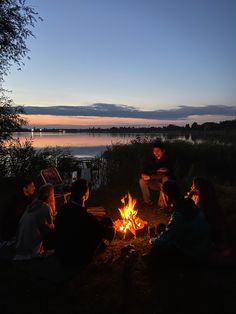 group of people sitting around a campfire at dusk