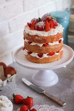 a cake with strawberries on top sitting on a plate next to an egg shell