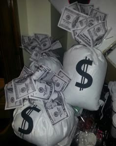 several bags filled with money sitting on top of a desk next to a pile of cash