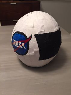 a paper mache ball with nasa on it sitting on a table next to a dresser