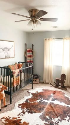 a baby's room with a cow rug and ceiling fan