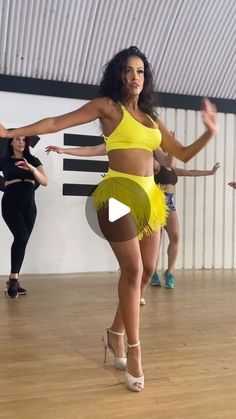 a group of women dancing in a dance studio with one woman wearing a yellow outfit